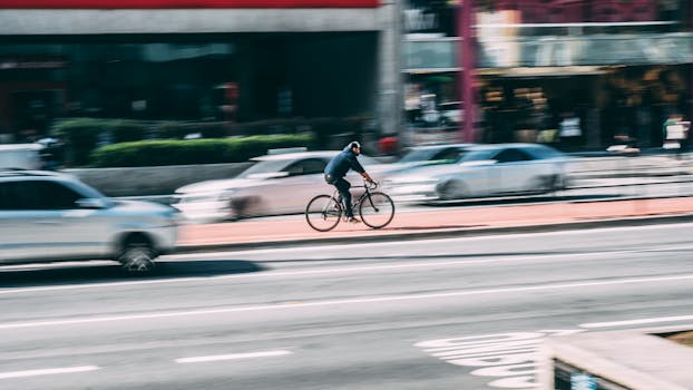 A cyclist rides swiftly through a bustling city street, capturing urban dynamics.